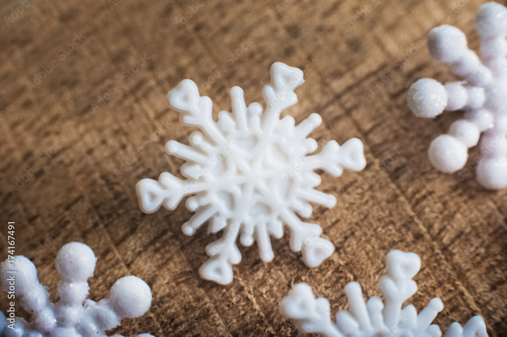 Beautiful white plastic snowflakes close-up on a wooden background.