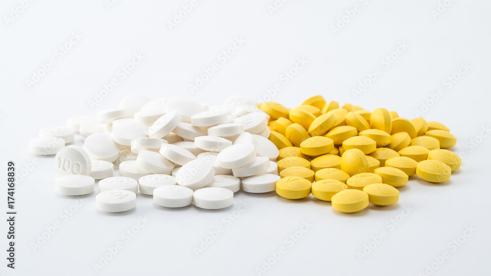 pile of white and yellow pills on white background pile of white and yellow pills on white background