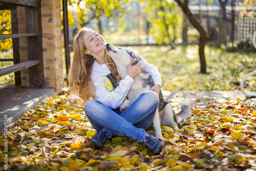 Happy girl in hugging husky dog in the autumn park