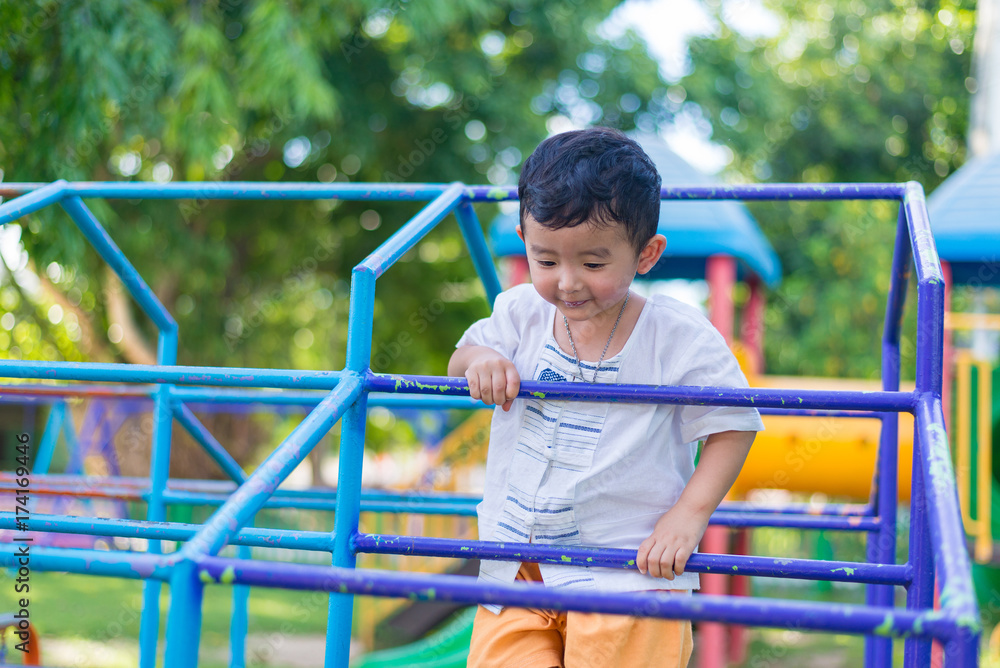 Asian boy hang the metal bar at outdoor playground. Asian boy hang the metal bar at outdoor playground.
