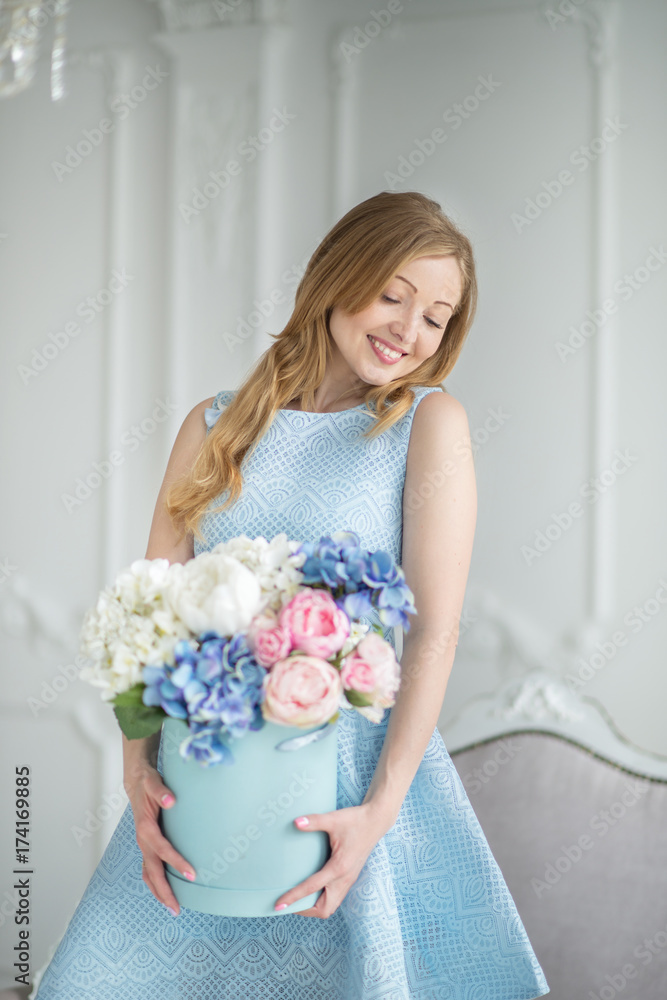 Beautiful girl in blue dress  with bouquet of flowers in room, close-up