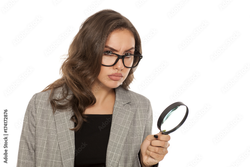 Beautiful young serious woman looking trough the magnifying glass Beautiful young serious woman looking trough the magnifying glass