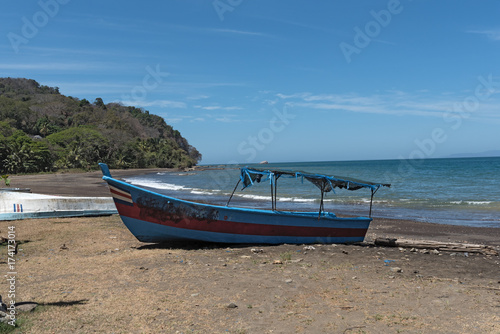 blue boat on the beach of the pacific ocean in Costa Rica
