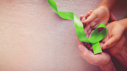 Adult and child hands holding Lime Green Ribbon, panoramic banner background, Mental health awareness and Lymphoma Awareness