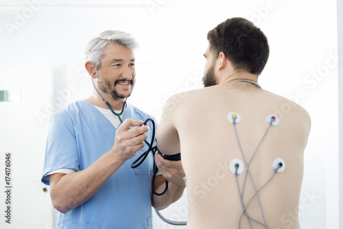 Doctor Examining Patient With Electrodes Attached On Back