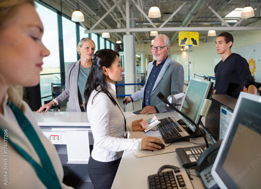 Naklejka premium Staff Checking Passport On Computer While Passengers Waiting In 
