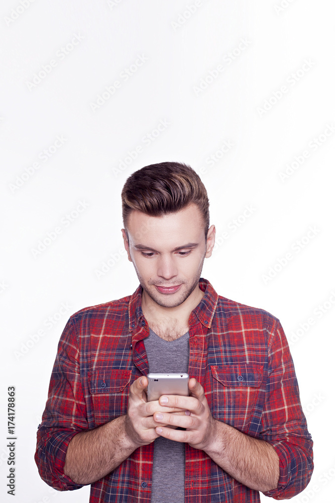 Handsome smiling man in checkered shirt holding smartphone and typing sms isolated on white background. Handsome smiling man in checkered shirt holding smartphone and typing sms isolated on white background.