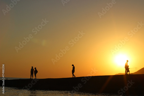 silhouette of people in the sun  sunset  silhouettes of people on the pier  evening walk