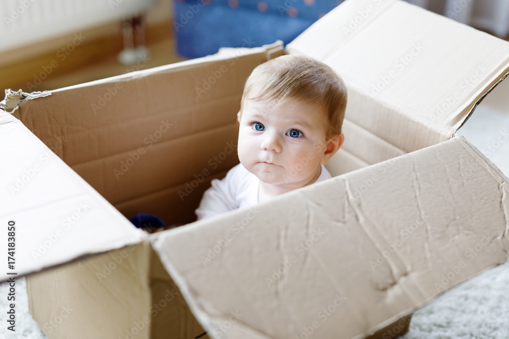 Adorable baby girl sitting in a post box. Cute baby with blue eyes Adorable baby girl sitting in a post box. Cute baby with blue eyes