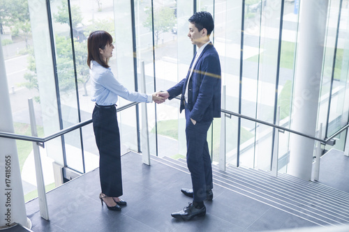 The business couple is shaking hands in the middle of the stairs