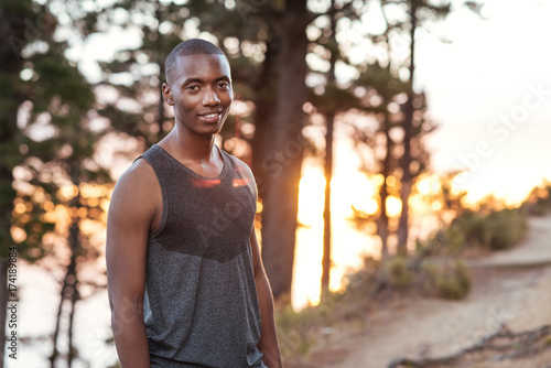 Smiling African man standing on a trail while out jogging