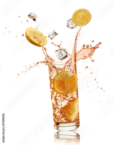 glass full of orange drink with orange slices and ice cubes falling and splashing, on white background