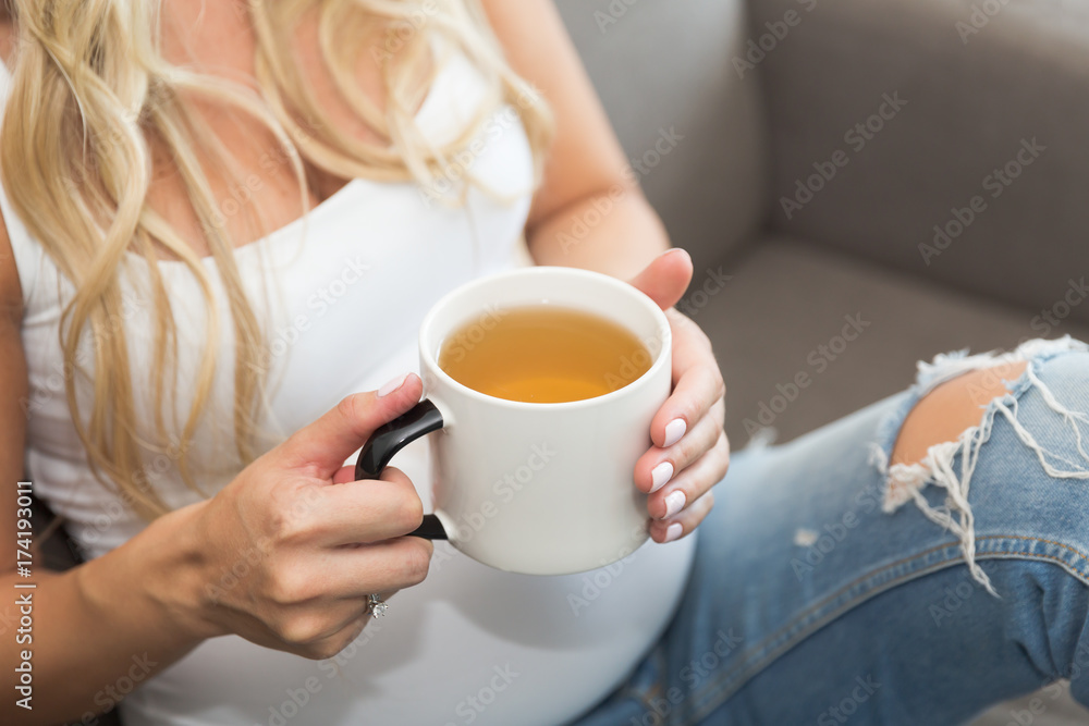 Pregnant long blond hair woman holds a mug of tea Pregnant long blond hair woman holds a mug of tea