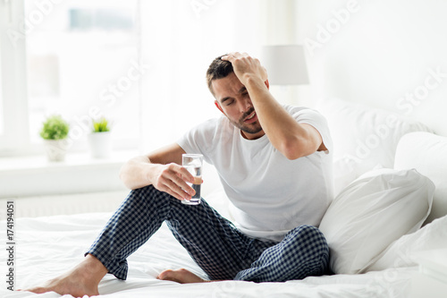 man in bed with glass of water at home photo