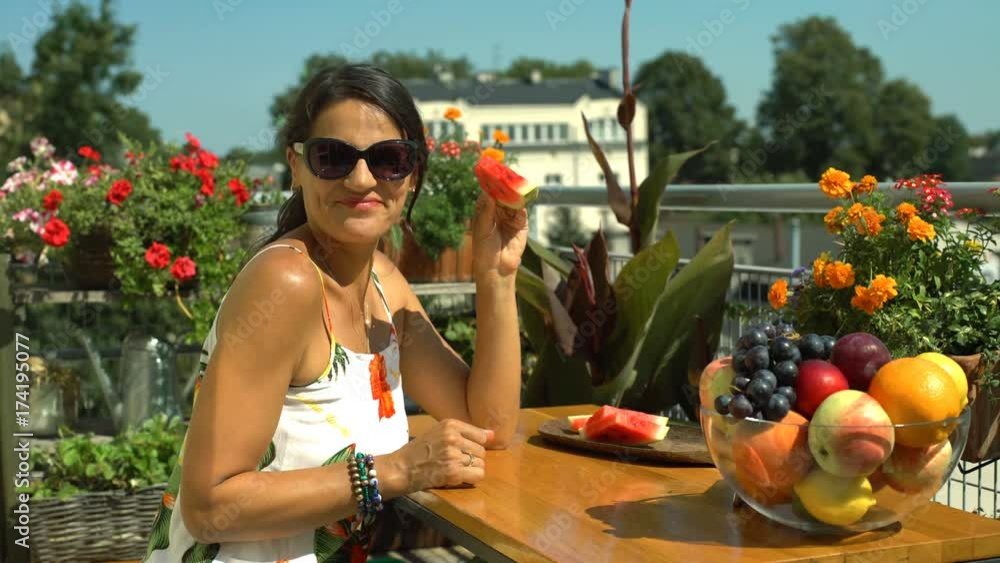 Beautiful woman smiling and eating watermelon on balcony
Beautiful woman smiling and eating watermelon on balcony