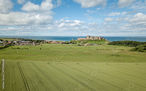 Bamburgh village and Castle, England. A drone view of the Northumberland landmark on the coast between the English countryside and the North Sea.