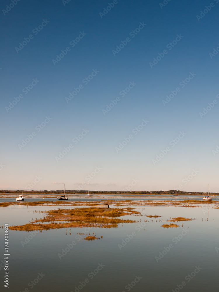 peaceful blue space river estuary scene outside bright sunny day boats moored
