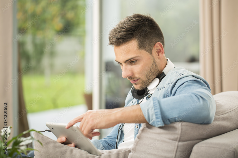 Man relaxing in sofa with tablet and headphones
