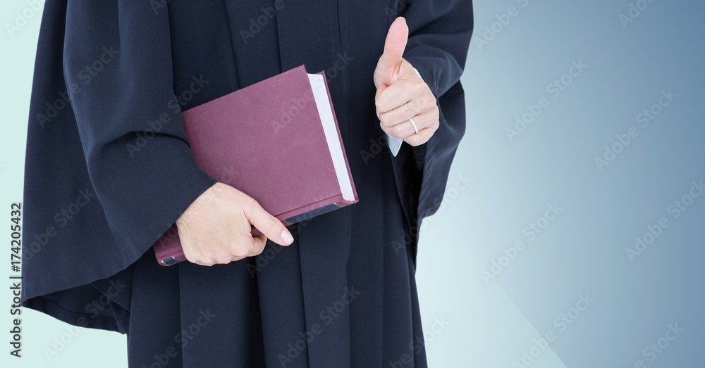 Female judge mid section with book and thumbs up against blue Female judge mid section with book and thumbs up against blue