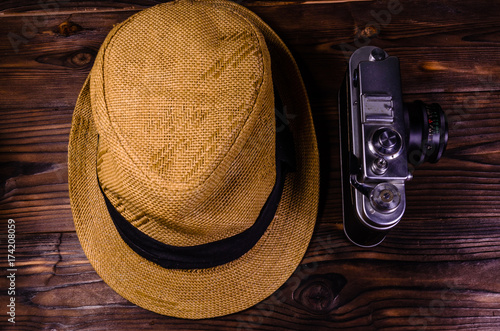 Old rangefinder camera and hat on a wooden table. Top view