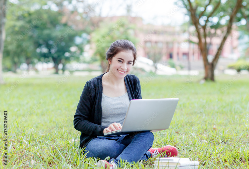female student sitting on the green field with laptop computer female student sitting on the green field with laptop computer