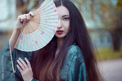 Portrait of young beautiful Asians in grey kimono and with a fan