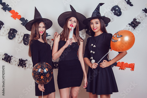 Women in witch halloween costumes standing with a knife and balloons.