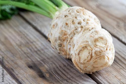 Fresh raw celery root with green stalk on rustic wooden background. Copy space