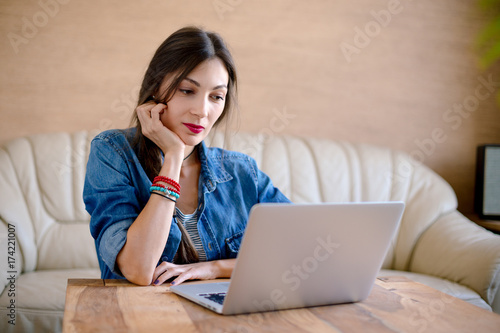 Beautiful young woman looking to laptop screen