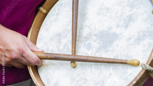 Dettaglio di un suonatore di tamburo vestito in costume rosso con abiti medievali. Le bacchette di legno sono tenute saldamente in mano. Lo strumento musicale è rifinito in legno, dunque molto pesante photo