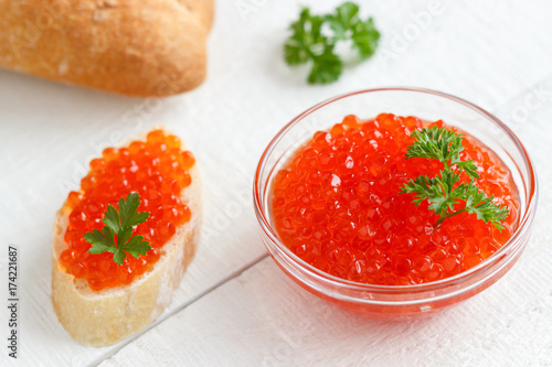 Red salmon caviar in glassware on a white wooden background