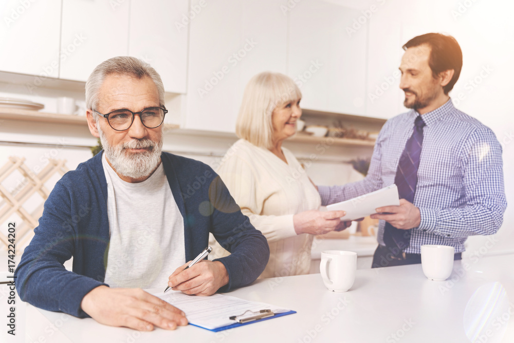 Positive aged man signing papers Positive aged man signing papers