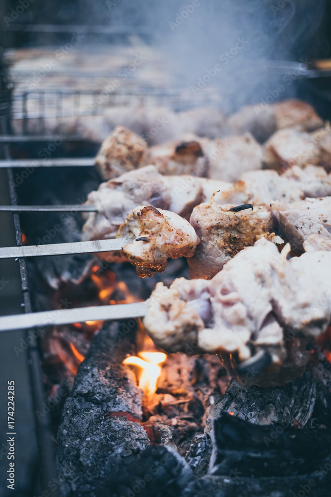 Grilled kebab cooking on metal skewers (grill). Roasted meat cooked at barbecue with smoke. Close up BBQ fresh pork meat chop slices. Traditional eastern dish, shish kebab. Grilled kebab cooking on metal skewers (grill). Roasted meat cooked at barbecue with smoke. Close up BBQ fresh pork meat chop slices. Traditional eastern dish, shish kebab.