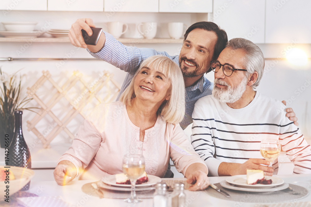 Joyful man making selfies with his aged parents Joyful man making selfies with his aged parents