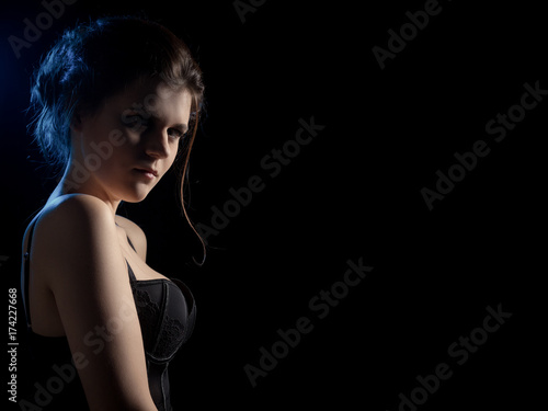 beautiful sad young woman on black background with copy space looking at camera