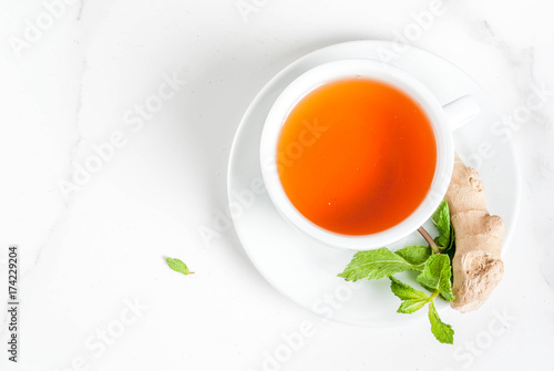 Cup of ginger tea with lemon,fresh mint and honey, on white marble table, copy space top view