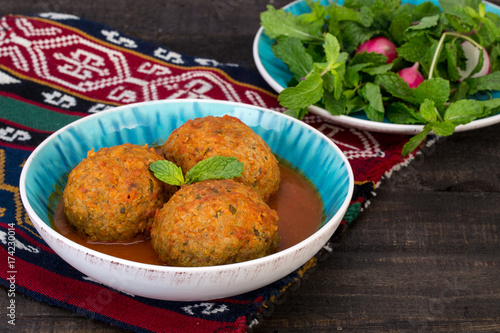 Koofteh Tabrizi Large Meatballs Stuffed With Dried Fruits, Berries And Nuts In Tomato Turmeric Broth A Traditional Azeri And Iranian Dish Served In Turquoise Bowl and Herbs