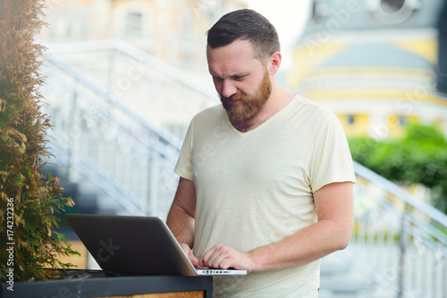 young man with laptop working outdoors in the city
