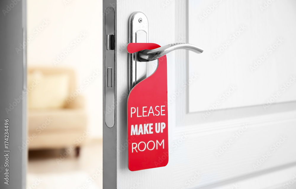 Naklejka premium Open door with sign PLEASE MAKE UP ROOM on handle at hotel