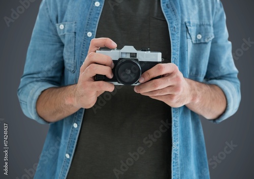 Millennial man mid section with camera against grey background © vectorfusionart