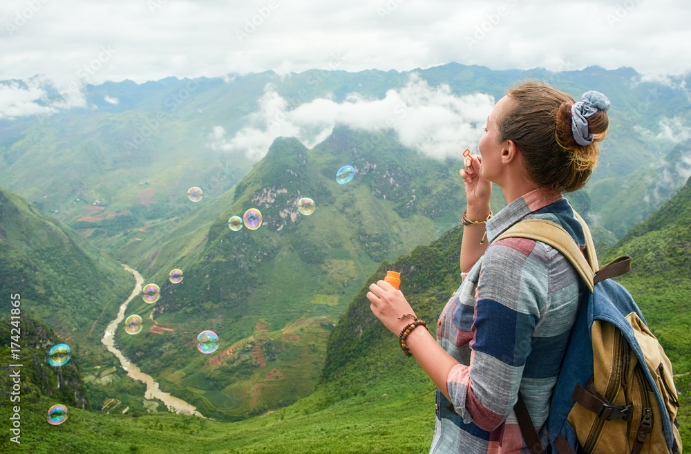traveller woman blowing soap bubbles in mountains.