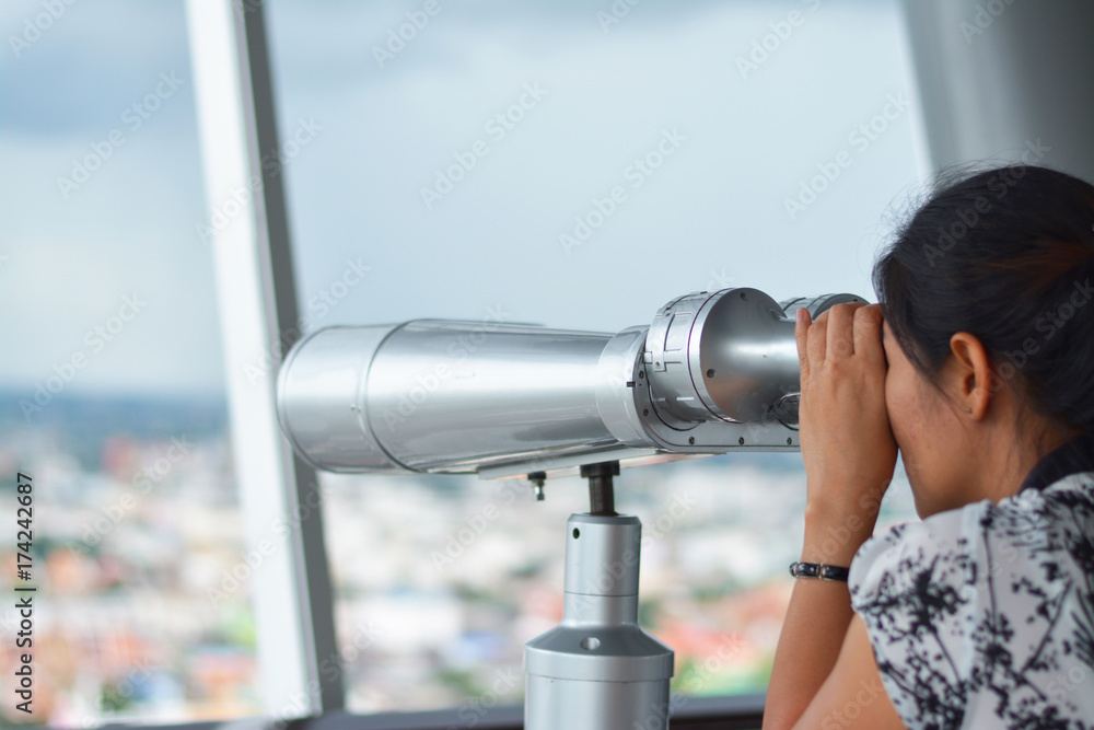 Girl looking city view with binoculars.