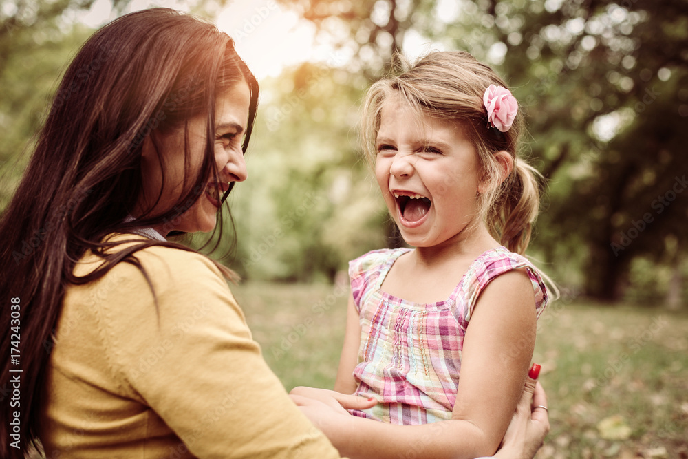 Mother and daughter outdoors in a meadow. Mother and daughter having funny conversation. Mother and daughter outdoors in a meadow. Mother and daughter having funny conversation.