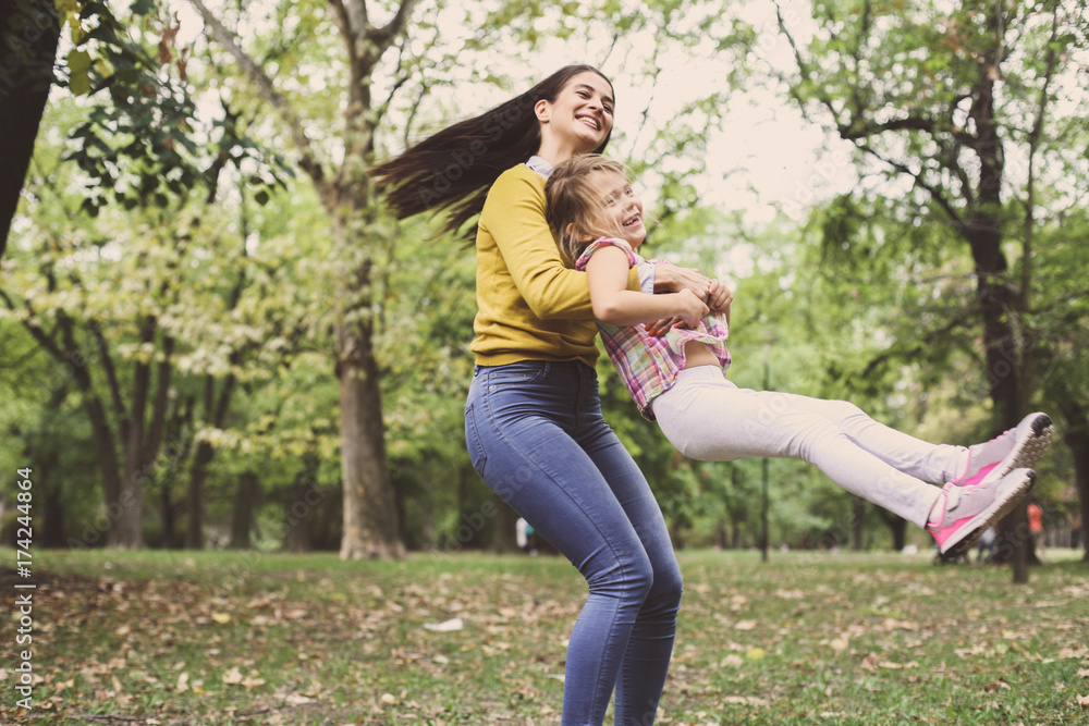 Mother and daughter playing together. Mother turns her daughter into a circle in the meadow. Mother and daughter playing together. Mother turns her daughter into a circle in the meadow.