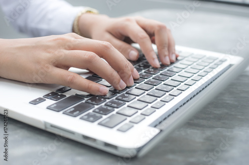 Close up hands of an employee is using a computer notebook by typing on keyboard at the desk.