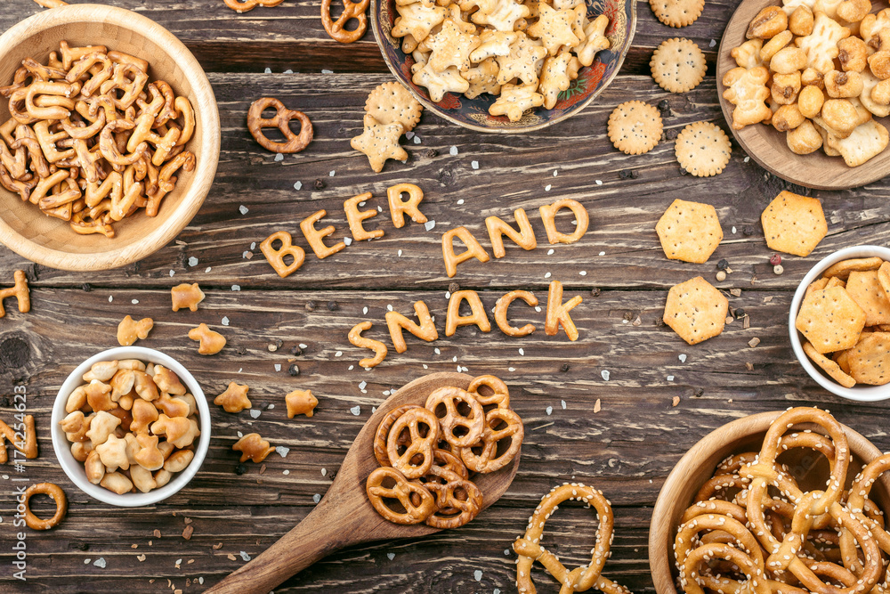 Fototapeta premium Snacks on wooden table. Words- Beer and snack, made of salty crackers letters. Top view