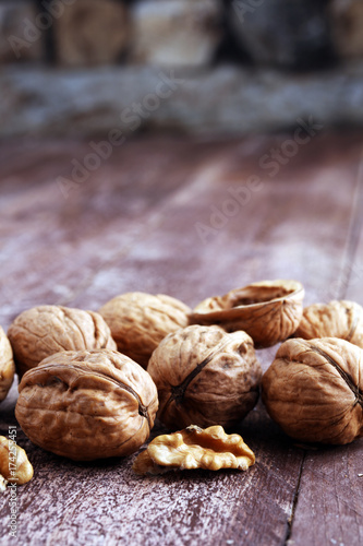 Walnut kernels and whole walnuts on rustic old wooden table.