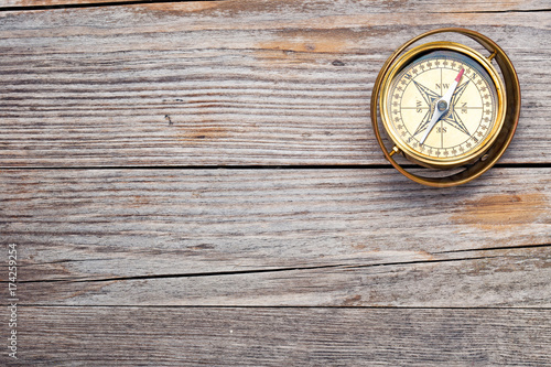 old-fashioned brass compass on rustic wooden table