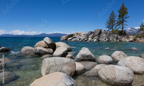 Pine trees, rocks, and snowy mountain at Sand Harbor, Lake Tahoe, Nevada on a sunny winter day