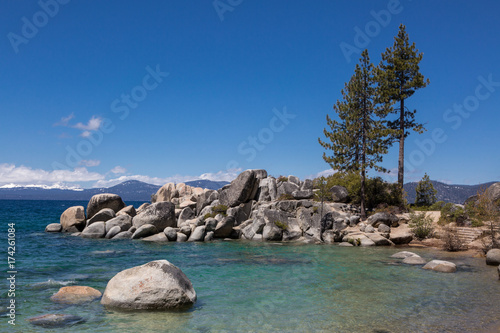 Pine trees, rocks, and snowy mountain at Sand Harbor, Lake Tahoe, Nevada on a sunny winter day